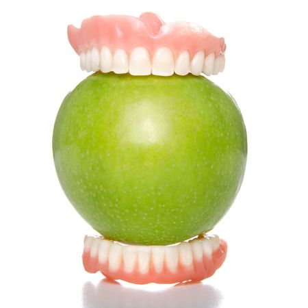 False teeth having a big bite into a green appleの写真素材