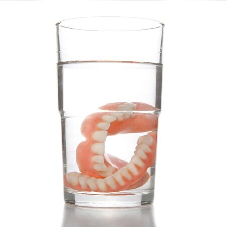 False teeth having a swim in transparent water glass