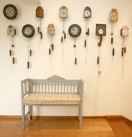 Wooden chair and many coocoo clocks on wall in entrance of houseの写真素材
