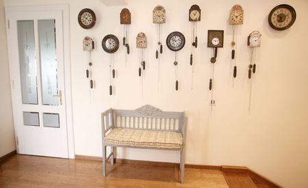 Wooden chair and many coocoo clocks on wall in entrance of houseの写真素材