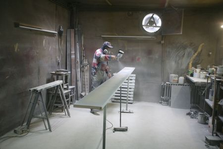 Man painting with spray paint gun in his home workshopの写真素材