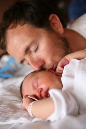 Father kissing his newborn baby child in hospital の写真素材