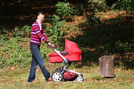 Father pushing pram in park on a sunny autumn day の写真素材