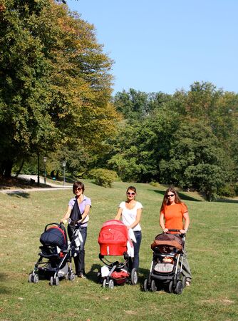 Mothers pushing their prams through the park in summerの写真素材