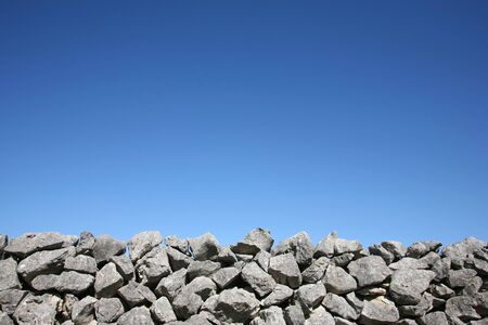Dry stone wall on blue sky backgroundの写真素材