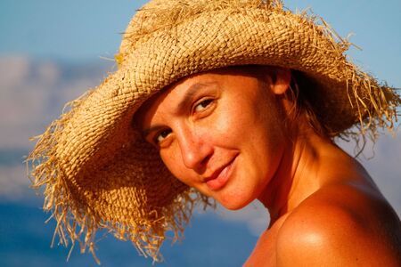 a portrait of a young woman with a straw hat on the beachの写真素材