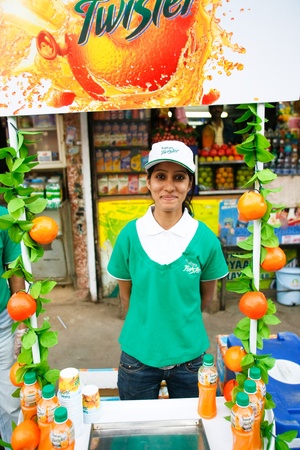 DELHI - FEBRUARY 26:  Hostess trying to promote artificial fruit juices in front of a traditional fresh fruit stall on February 26, 2008 in Delhi, India. This is where traditional meets modernityのeditorial素材