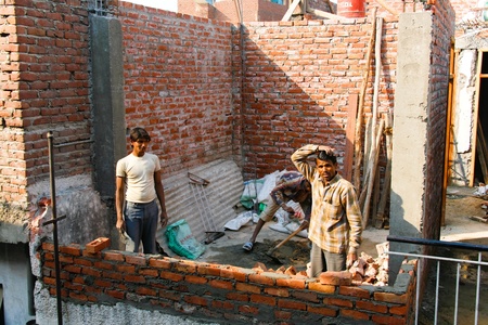 DELHI - FEBRUARY 29: Three men laying a brick wall for a house on February 29, 2008. Contributing to India's booming economy.のeditorial素材