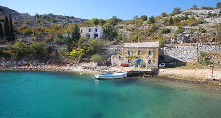 View of old stone house with a wooden boat moored in little bayの写真素材