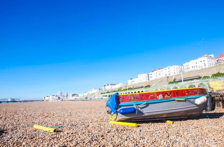 BRIGHTON, UK - FEBRUARY 8, 2011: Old boat on Brighton's pebble beach on February 8 2011 in Brighton, UK. Brighton beach is a famous venue for all events, such as concerts, markets and drinking.のeditorial素材