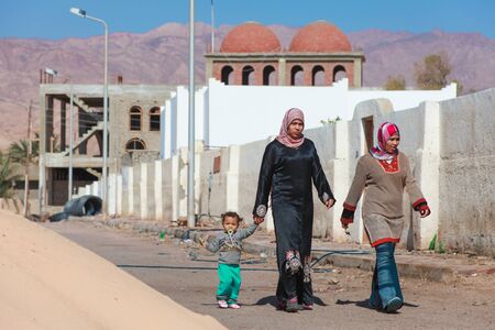 DAHAB, EGYPT - FEBRUARY 2, 2011: Women in traditional dresses walking with child on February 2, 2011 in Dahab, Egypt. Hijab is a veil which covers the hair and neck.のeditorial素材