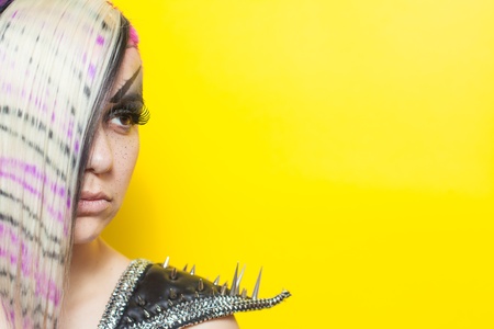 Close up of woman with multicoloured hair on yellow background