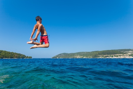 KOMIZA, CROATIA - JULY 6, 2012  A boy jumps into the sea on the head on July 6, 2012 in Komiza, Croatia  Children having fun jumping in the sea のeditorial素材