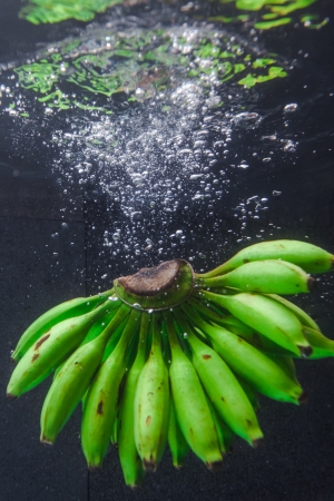 Bunch of bananas splashing into fresh waterの写真素材