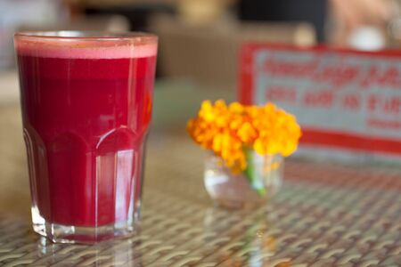 Full glass of beetroot and carrot juice decorated with flower in vegetarian restaurantの写真素材