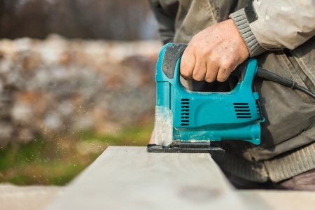 Carpenter cutting wood en with an electric jigsaw