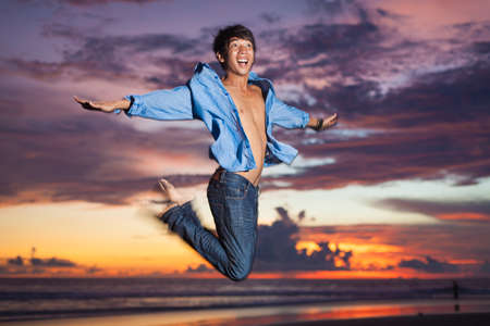 Young asian man jumping at sunsetの写真素材