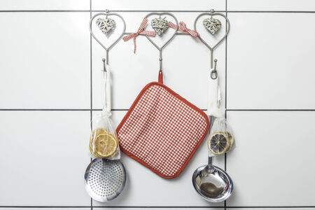 Kitchen utensils hanging on the white tiled kitchen wall.の写真素材