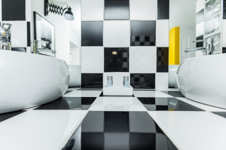 Two sinks in modern bathroom with checkered black and white tiles on walls.のeditorial素材