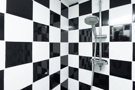 Modern shower in a bathroom with checkered black and white tiles.の写真素材