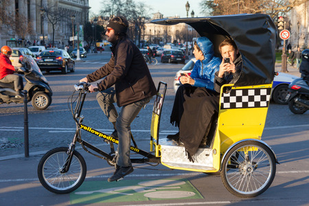 PARIS, FRANCE - JANUARY 6, 2012: Tourists driving in bicycle taxi and taking photos. のeditorial素材