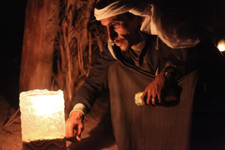 DAHAB, EGYPT - JANUARY 24, 2011: Bedouin sits by the light at night. Bedouin culture still survives in the Sinai, where there is a growing appreciation of its value and its fragility.のeditorial素材
