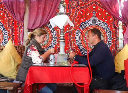 DAHAB, EGYPT - JANUARY 24, 2011: Couple sitting in the oriental bar with nargile on the table. These...