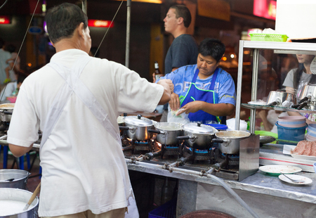 BANGKOK, THAILAND - JANUARY 9, 2012: Man prepares traditional Thai food on a street food stall. Everyday thousands of tourists and locals buys food on these stalls.のeditorial素材