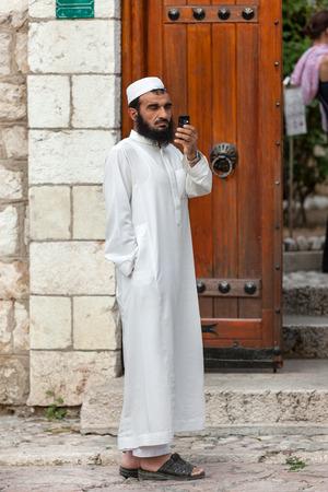 SARAJEVO, BOSNIA AND HERZEGOVINA - AUG 13: Muslim man with cell phone stands on street on August 13, 2012 in Sarajevo, B&H. Muslims comprise the single largest religious group in B&H.のeditorial素材