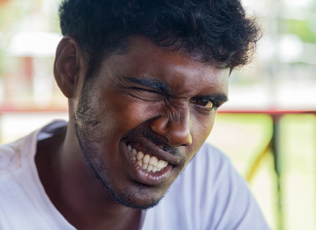 WELIGAMA, SRI LANKA - MARCH 7, 2014: Portrait of young local man winking for camera. Local people in...