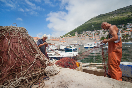 DUBROVNIK, CROATIA - MAY 26, 2014: Local fishermen in city port holding fishing net. Thanks to local fishermen Dubrovnik is brimming with fresh seafood.のeditorial素材