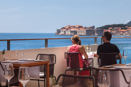 DUBROVNIK, CROATIA - MAY 26, 2014: Young couple sitting on restaurant terrace with view on Old town and Adriatic sea.のeditorial素材