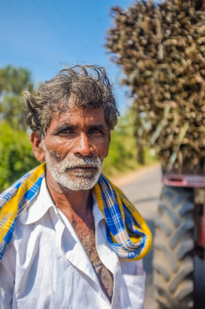 HAMPI, INDIA - 28 JANUARY 2015: Portrait of Indian worker next to truck loaded with sugarcaneのeditorial素材