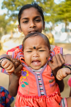 HAMPI, INDIA - 31 JANUARY 2015: Indian baby with bindi crying while being held by family memberのeditorial素材