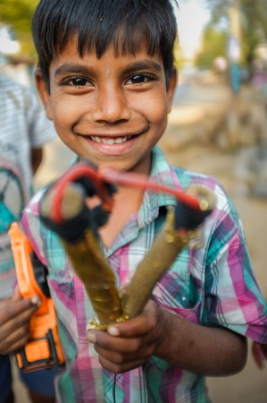 HAMPI, INDIA - 31 JANUARY 2015: Indian boy holding slingshot and toy truckのeditorial素材
