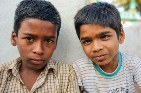 hAMPI, INDIA - 31 JANUARY 2015: Two Indian boys sitting in street next to a wallのeditorial素材