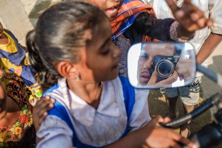 HAMPI, INDIA - 01 FEBRUARY 2015: Indian children playing around a motorbike and looking at photographer in rearview mirrorのeditorial素材