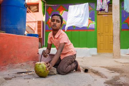 KAMALAPURAM, INDIA - 02 FABRUARY 2015: Indian boy opening a coconut infront of house in a town close to Hampiのeditorial素材
