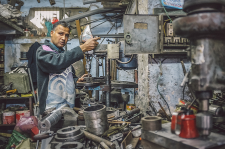 JODHPUR, INDIA - 07 FEBRUARY 2015: Indian mechanic works in workshop filled with scattered tools and machines. Post-processed with added grain and texture.のeditorial素材