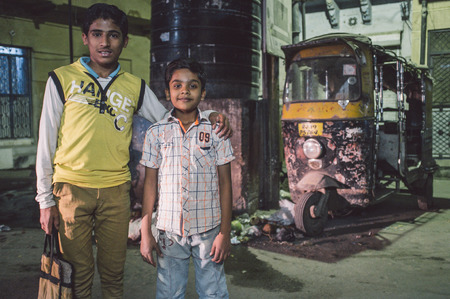 JODHPUR, INDIA - 17 FEBRUARY 2015: Two young boys stand in street with rickshaw parked in background. Post-processed with grain and texture.のeditorial素材