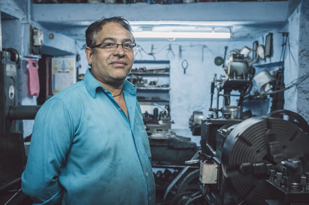 JODHPUR, INDIA - 17 FEBRUARY 2015: Mechanic working late in workshop with scattered equipment and...
