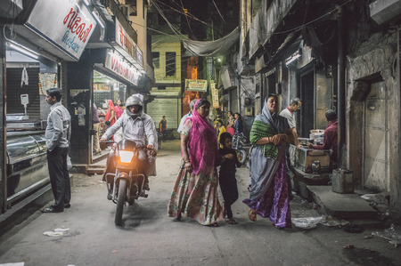 JODHPUR, INDIA - 16 FEBRUARY 2015: Man on motorbike passes two women with child and man ordering food. Post-processed with grain and texture.のeditorial素材