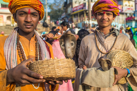 VARANASI, INDIA - 23 FEBRUARY 2015: Two Indian boys dressed up in religious clothes hold cobras in baskets.のeditorial素材