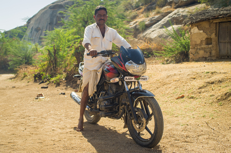 GODWAR REGION, INDIA - 13 FEBRUARY 2015: Indian man shows off his motorbike in courtyard.のeditorial素材