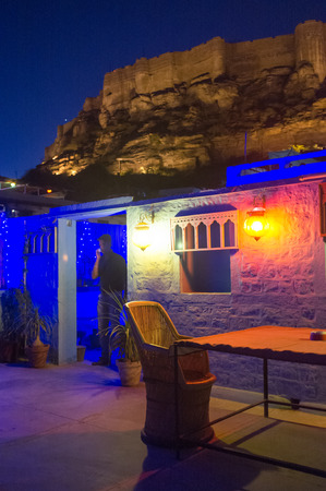 JODHPUR, INDIA - 16 FEBRUARY 2015: Man on phone on restaurant terrace with Mehrangarh Fort in background.のeditorial素材