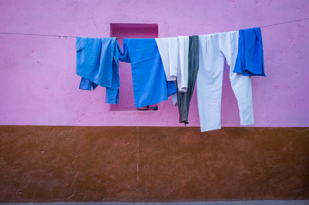 GODWAR REGION, INDIA - 12 FEBRUARY 2015: Clothes hang on wire next to pink and brown wall.のeditorial素材