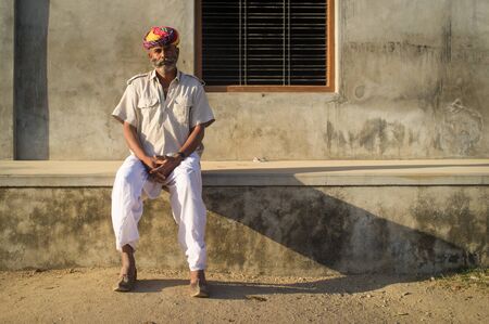 GODWAR REGION, INDIA - 14 FEBRUARY 2015: Adult Indian man with colorful turban and curled mustache sits in street.のeditorial素材