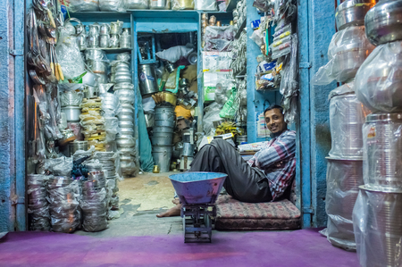 JODHPUR, INDIA - 10 FEBRUARY 2015: Worker sits and rests before closing time. Stores with kitchen pottery and other products made from metal are common on Asian markets.のeditorial素材