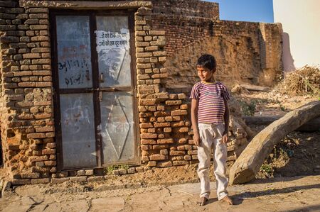 GODWAR, INDIA - 12 FEBRUARY 2015: Little barefoot boy stands in street next to ruin house.のeditorial素材