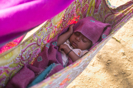 GODWAR, INDIA - 12 FEBRUARY 2015: Indian baby sleeps in makeshift crib made from blanket.のeditorial素材